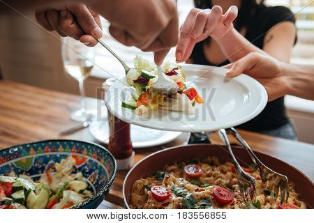 Closeup of people putting food on the plate and having dinner together