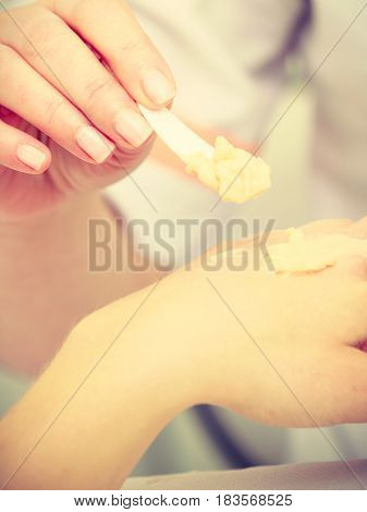 Woman Applying Cream On Hand Using Spatula