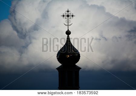 Photo of an Orthodox Christian cross on a background of gloomy clouds