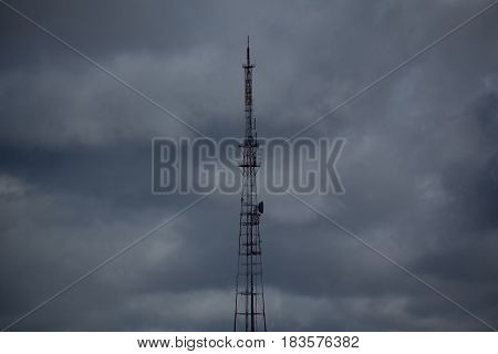 Photo of a television tower in the background of gray clouds