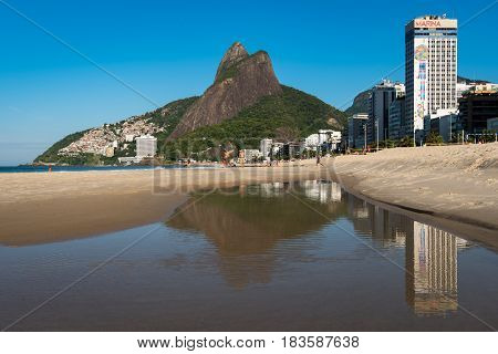 Rio de Janeiro, Brazil - April 6, 2017: Mountains reflecting in water of Leblon beach. Leblon is Latin America's most expensive land.