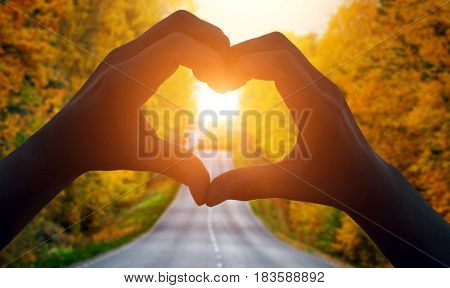 Cropped Hand Making Heart Shape and a road