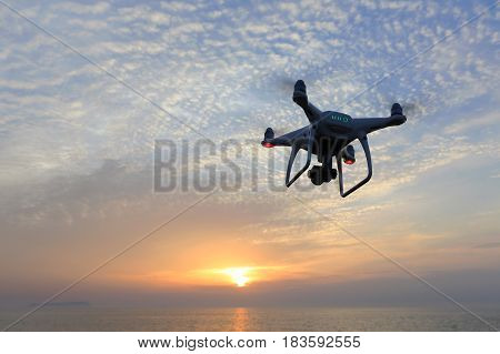 KAGAWA, JAPAN - APRIL 22, 2017: Remote controlled drone Dji Phantom4Pro equipped with high resolution video camera flying above the sea against a sunset sky.