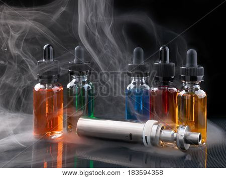 Electronic cigarette or vaping device and assorted vape liquids within vapor on black background