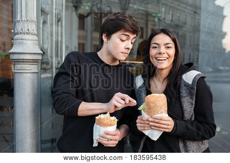 Brother trying to eat burger of his laughing sister in the street