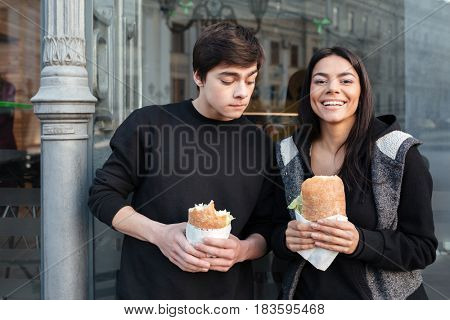 Brother looking at sister's burger near cafe