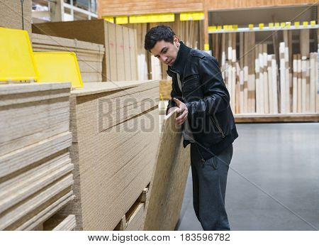 male customer choosing flakeboard or Oriented strand board OSB in the supermarket. Buying Construction and building material