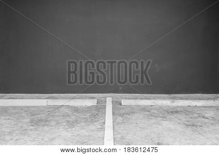 Closeup surface line slot for parking on cement floor with blurred dark gray cement wall in the garage textured background in black and white tone with copy space