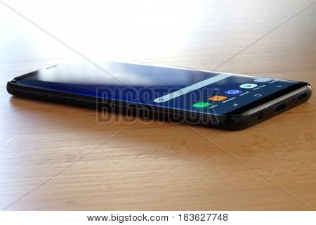 Koszalin, Poland - 27 April, 2017: Black Samsung Galaxy S8 on wooden table. Samsung S8 are new generation smartphone from Samsung. The Samsung S8 is smart phone with multi touch screen