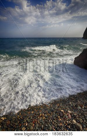 Sea waves crashing on the shore and flowing above seashore pebbles. spindrift