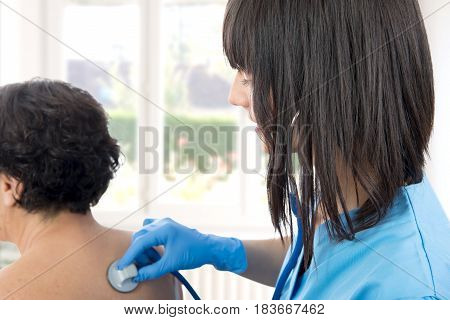 young female doctor examines a patient with a stethoscope