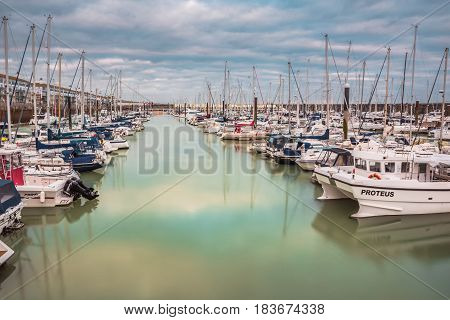 Boats yachts and fishing boats moored at Brighton Marina docs on a cloudy day.