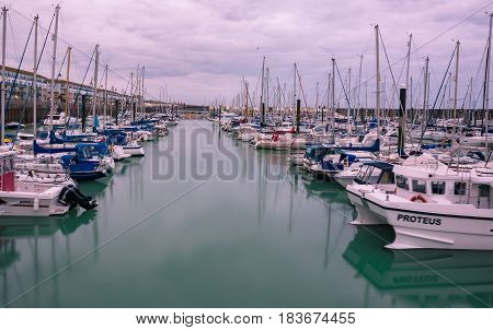 Boats yachts and fishing boats moored at Brighton Marina docs on a cloudy day.