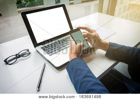 Young businessman working with laptop and smart phone on his desk in office.