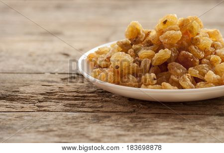 dried grapes close up on white plate on wooden background