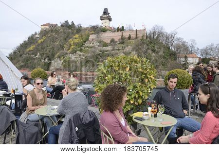 GRAZ, AUSTRIA - MARCH 20, 2017: People at the terrace of the Kastner and Ohler warehouses with views to Tower of the Clock in Graz the capital of federal state of Styria Austria.