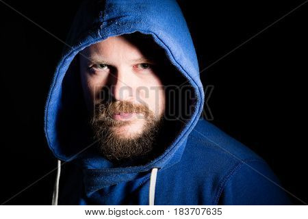 Solid bearded middle-aged man in a hood  portrait on black background