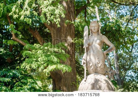 Unknown women mermaid sculpture on trees background in Milano city center park Shiny summer day