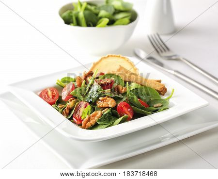 A special salad with spinach seitan cherry tomatoes and walnuts.
