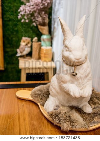 Whtie rabbit made from paster for decoration with an iron bell in his neck.