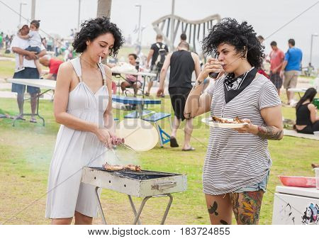 TEL AVIV, ISRAEL. May 6, 2014. Two young unknown Israeli women make barbecue on the Independence day of Israel in a public park. Israel Independence Day party stock image.