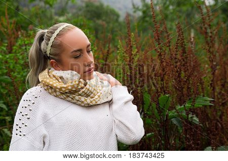 Pretty young reflective woman standing looking up in a mountain