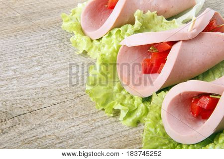 Roll of homemade sausage with vegetables on a wooden background. Space for text