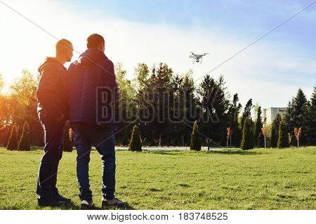 Man controls a quadrocopter. Selective focus on drone men is blurred. Launching a quadrocopter in the park