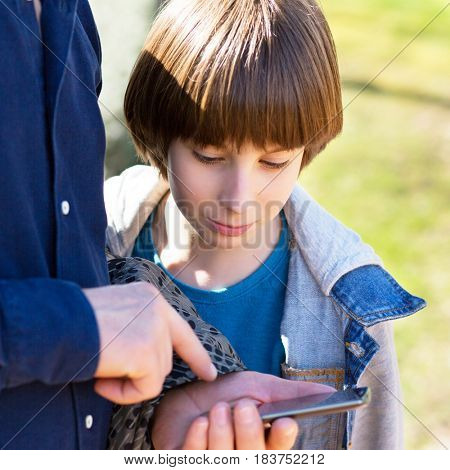 Father with son using smart phone outdoor together. Young boy with his father in spring park.