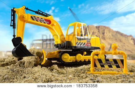 Excavator toy standing on a construction ground on a sunny day. Background used from Pixabay under cc0 license.