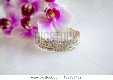 Zirconium bracelet lies on the background of purple orchids