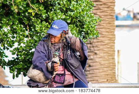Capetown, South Africa - August 25, 2007;  Homeless ethnic African man in ragged clothes and homemade decorations sitting beside street in Capetown.