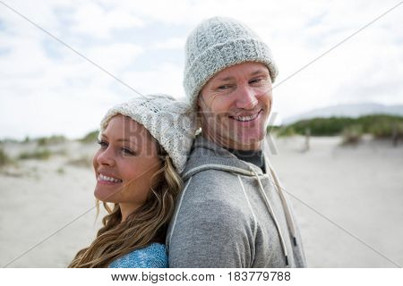Mature couple standing back to back on beach