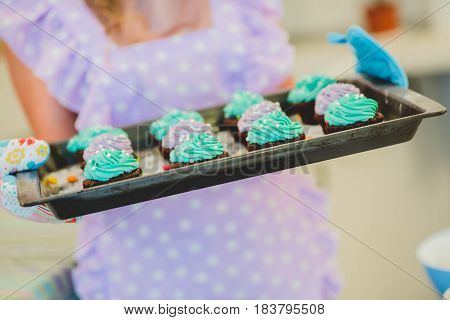 cupcakes are on the tray. Female hands holding dessert.Multi-colored cakes