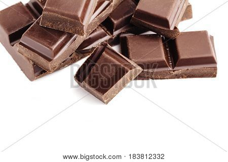 Pieces of bitter dark chocolate bar cubes on heap isolated on white background close-up view.