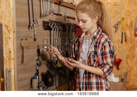 It is rather heavy thing. Determined smart vibrant child studying tools her dad using for repairing motorbikes