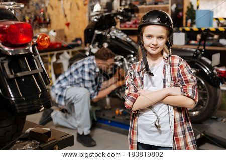   Persistent clever cool child imagining herself being a mechanic while helping her father fixing the bike