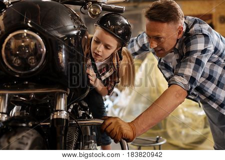 It is so smooth. Smart encouraged emotional girl seeming charmed by dads vehicle while sitting on it and wearing a helmet