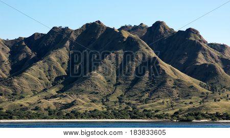 Coastline of mountains with green vegetation and blue ocean water at Labuan Bajo in Flores Indonesia.