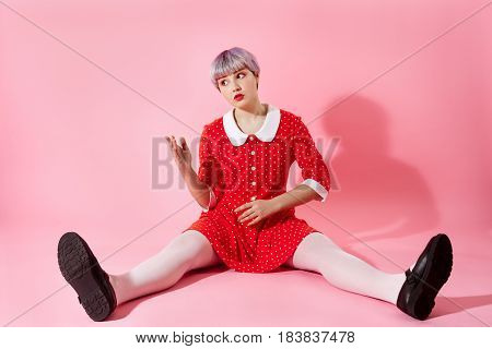 Picture of beautiful dollish girl with short light violet hair wearing red dress over pink background. Copy space.