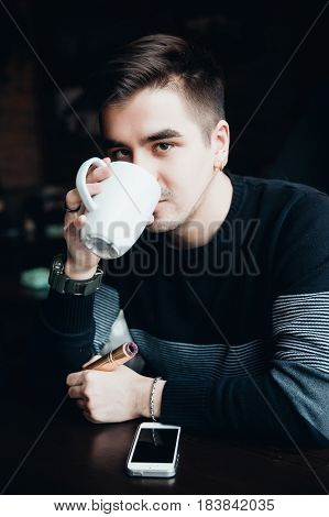man holds a mug of coffee in the morning and smokes a vape. Good morning concept.