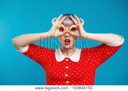 Close up portrait beautiful dollish girl with short light violet hair wearing red dress over blue background. Copy space.