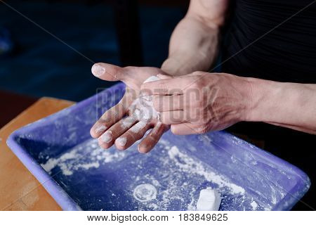 Man athlete coating his hands in powder chalk magnesium. Ready for workout training. Magnesium of gymnastic