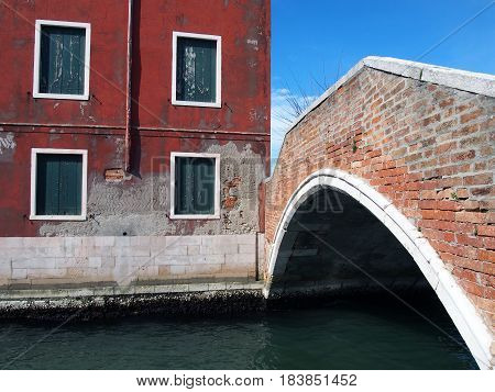 footbridge in murano venice with red building and peeling paint