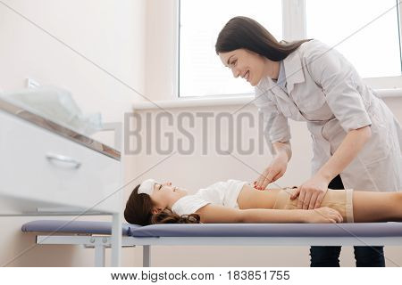 Medical examination. Nice pleasant young girl lying on the medical med and being examined by the doctor while visiting the hospital