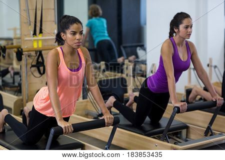 Fit women exercising on reformer in gym