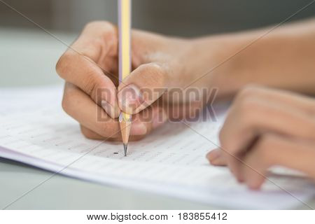 students hand testing doing examination with pencil drawing selected choice on answer sheets in school exam at college