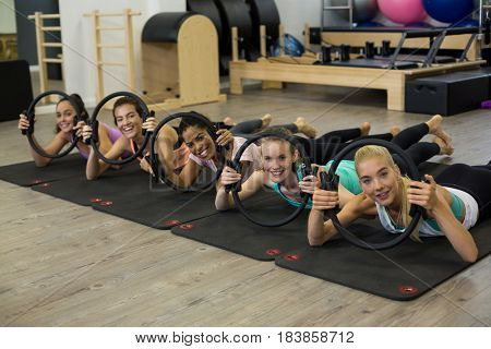 Group of fit women exercising with pilates ring in gym