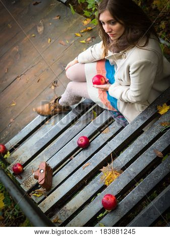 Girl sitting down the stairs with apples.