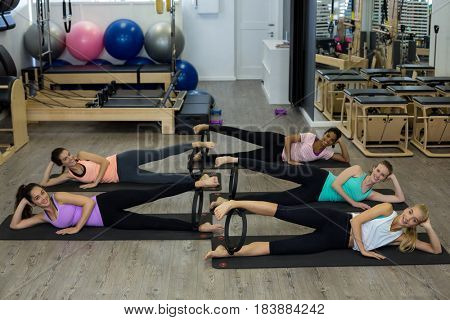 Group of fit women exercising with pilates ring in gym